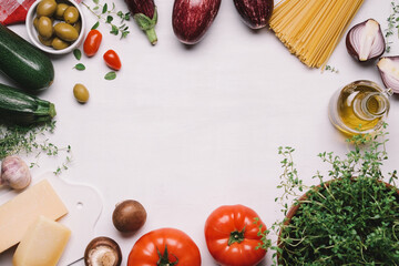 Ingredients of italian food. Spaghetti, tomatoes, olives, olive oil, parmesan, traditional mediterranean vegetables and herbs. White food background