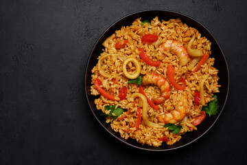 Fried rice with seafood and vegetables. Squid rings, shrimp, red bell pepper, carrot, onion ingredients. Asian cuisine