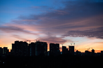 Fototapeta na wymiar Warm sunset over city landscape with tall buildings and sky scrapers' silhouette in the foreground