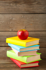 Composition of school books and an apple on grey wooden background