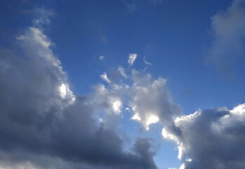 Fototapeta premium White and gray fluffy clouds illuminated by the sun on a blue sky background