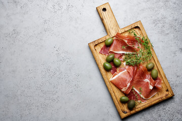 Jamon appetizer on cutting board. Traditional spanish or portuguese tapas. Gray food background