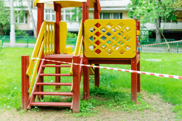 Fototapeta na wymiar A yellow slide for children's park is wrapped with red barrier tape. Prohibition of outdoor walks, prevention of the biological hazard of the coronavirus influenza covid-19. caution. selective focus