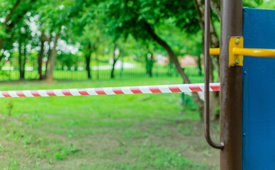 Fototapeta na wymiar Children's playground wrapped with red barrier tape. Outside. Prohibition of outdoor walks, prevention of the biological hazard of the influenza virus covid-19. coronavirus. selective focus