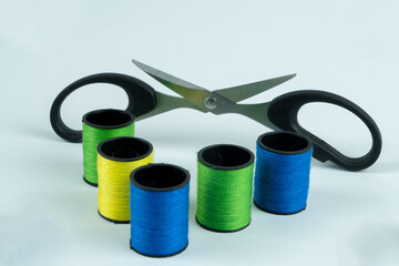 Colored spools of thread with scissors on a white background 