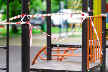 Fototapeta na wymiar The play park of amusement for young children is wrapped in red barrier tape. Prohibition of outdoor walks, prevention of the coronavirus influenza virus covid-19. equipment. selective focus