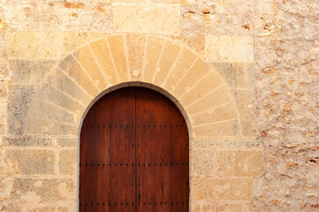 Stone facade with wooden door and stone arch of popular architecture