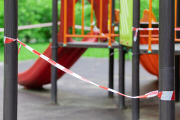 Fototapeta na wymiar The play park of amusement for young children is wrapped in red barrier tape. Outside. Prohibition of outdoor walks, prevention of the coronavirus influenza virus covid-19. spring. selective focus