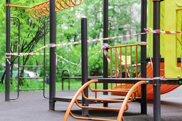 The play park of amusement for young children is wrapped in red barrier tape. Outside. Prohibition of outdoor walks, prevention of the coronavirus influenza virus covid-19. russia. selective focus