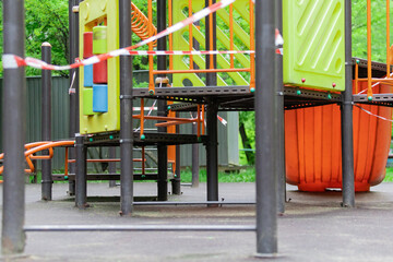 The play park for children is wrapped in red barrier tape. Prohibition of outdoor walks, prevention of the biological hazard of the coronavirus influenza virus. state of alarm. selective focus