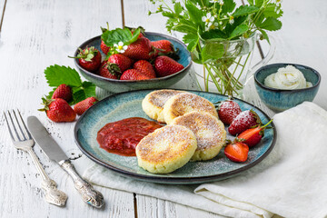 Cottage cheese pancakes (syrniki). Homemade cheesecakes from cottage cheese with sour cream, berries and milk. Traditional Russian dish. Close-up