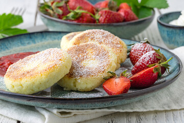 Frying homemade Cottage cheese pancakes Russian syrniki with strawberry on  plate. Breakfast time
