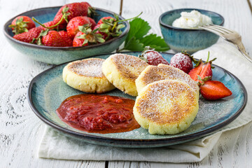 pancakes from cottage cheese with berries, powdered sugar and fresh mint, white wooden background, breakfast