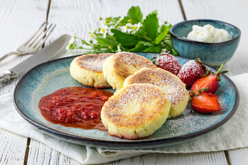 Frying homemade Cottage cheese pancakes Russian syrniki with strawberry on  plate. Breakfast time