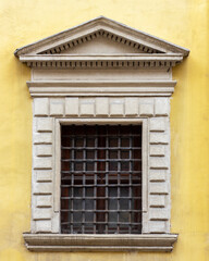 Fototapeta na wymiar Pediment above a window of an ancient european house. Window with a wrought iron lattice.