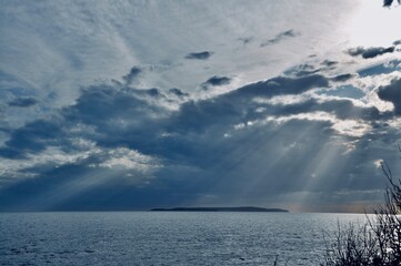 sailing boat in the sea, sun rays and small island Susak on horizon