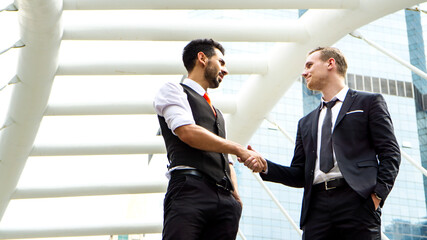 business people standing with handshake in front of building