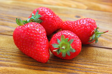 four red ripe strawberries on a wooden table