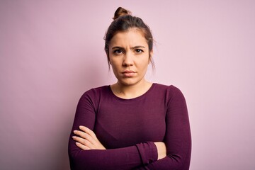 Obraz premium Beautiful young woman wearing casual bun hairstyle over pink isolated background skeptic and nervous, disapproving expression on face with crossed arms. Negative person.
