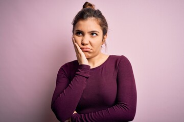 Beautiful young woman wearing casual bun hairstyle over pink isolated background thinking looking tired and bored with depression problems with crossed arms.