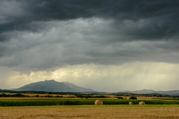 Fototapeta na wymiar Dark rain clouds over field of harvested wheat.