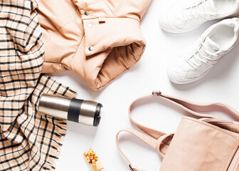 Fashion flat lay with long beige puff, scarf and sneakers on white background