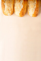 French baguettes in a row on light brown background with copy space. 