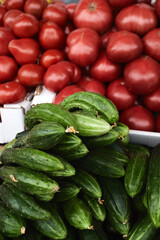 green cucumbers and red tomatoes in cardboard boxes in the organic market