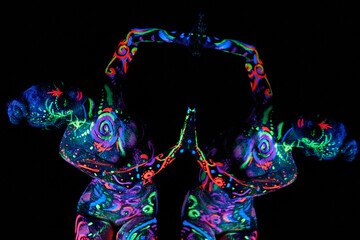 Art woman body art on the body dancing in ultraviolet light. Bright abstract drawings on the girl body neon color. Fashion and art woman, out of focus