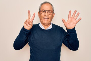 Fototapeta premium Senior handsome grey-haired man wearing sweater and glasses over isolated white background showing and pointing up with fingers number seven while smiling confident and happy.