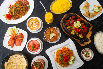 Table with typical Indian dishes, Biryani, chicken curry, tandoori, tikka masala, korma, rice pilaf.