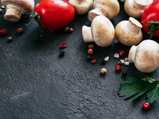 Food ingredients on black background, copy space Mini champignons, cherry tomatoes, herbs and spices top view or flat lay