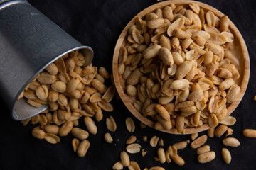 A pile of peanuts in a wooden plate on the black top