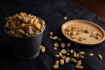 A pile of peanuts in a zinc cup on a black top