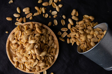 A pile of peanuts in a wooden plate on the black top