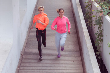 Two Healthy young female sporty women running in morning on street. Runner training outdoors in morning.
