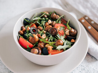 Salad with arugula, mini champignons, cherry tomatoes, black olives, pine nuts. Vegetarian salad...