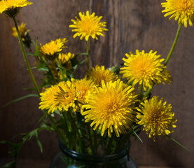 Bouquet of yellow dandelions on a wooden background, close-up
