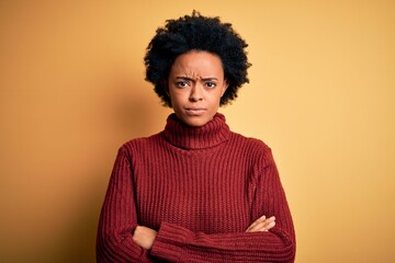 Fototapeta na wymiar Young beautiful African American afro woman with curly hair wearing casual turtleneck sweater skeptic and nervous, disapproving expression on face with crossed arms. Negative person.