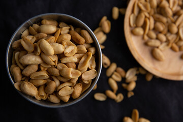 A pile of peanuts in a zinc cup on a black top