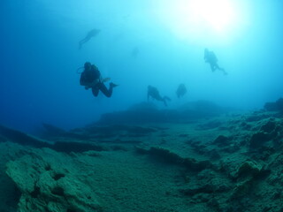 Fototapeta na wymiar scuba divers exploring scenery underwater sun beams and rays sun shine silhouette ocean scenery