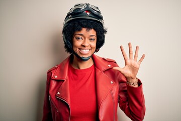 Young African American afro motorcyclist woman with curly hair wearing motorcycle helmet showing and pointing up with fingers number five while smiling confident and happy.