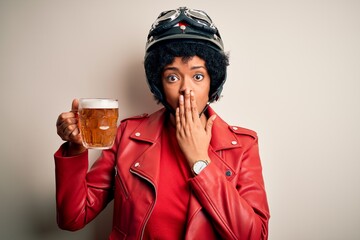 Young African American afro motorcyclist woman with curly hair drinking jar of beer cover mouth with hand shocked with shame for mistake, expression of fear, scared in silence, secret concept