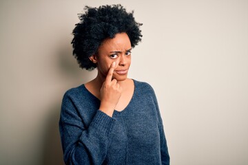 Fototapeta na wymiar Young beautiful African American afro woman with curly hair wearing casual sweater Pointing to the eye watching you gesture, suspicious expression