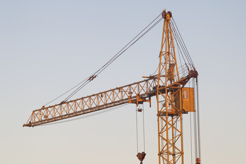 Yellow construction tower crane close-up on sky background