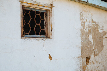 An old, crumbling window with a rusty bars on it. Damaged building