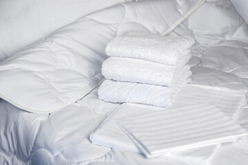 Towels are on bed. White bedding close-up. Clean terry towels on bedstead. Concept - bed linen at...