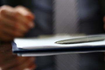 Silver pen lying on form clipped to pad closeup