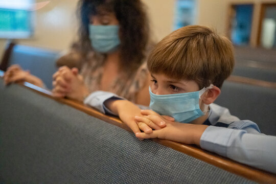 Family Praying Together In Church With Mask On. 