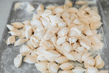 Raw dumplings from the dough in handmade flour lie on an iron tray